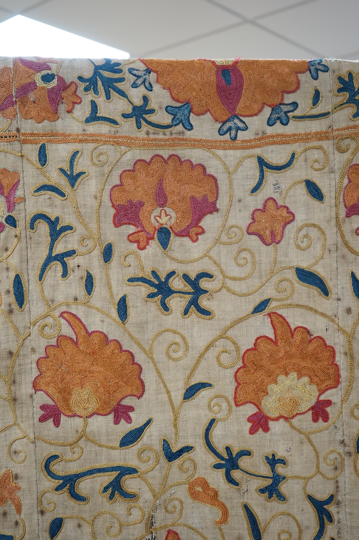 A 19th century, circa 1850-1880 hand embroidered Suzani wall hanging, probably from Uzbekistan. Worked on had woven linen, predominantly embroidered in orange, ochre, maroon and green silks in fine chain stitch with an o